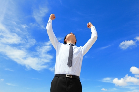 happy successful business man raised arms with sky in the background, asian peopleの写真素材