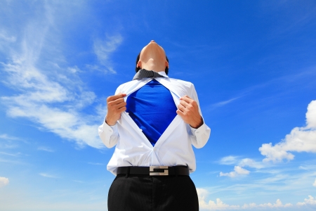 Business man pulling his t-shirt open, showing a superhero suit underneath his suitの写真素材