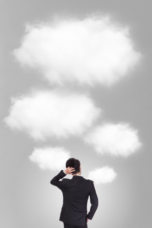 Back pose of a business person thinking with cloud and gray background, asian modelの写真素材