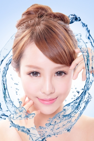 Beautiful portrait of woman with fresh skin in splashes of water , concept for beauty skin care isolated on blue background, asian modelの写真素材