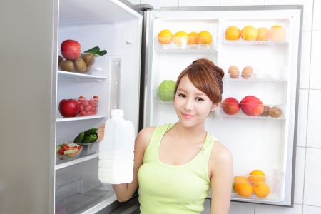 Healthy Eating Concept .Diet. Beautiful Young Woman drink milk near the Refrigerator. Fruits and Vegetables, asian modelの写真素材