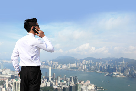 Happy business men call by smart phone on business architecture background, asia, hong kongの写真素材