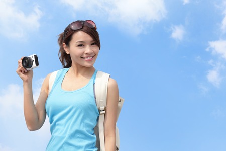 Happy woman traveler photo by camera with blue skyの写真素材