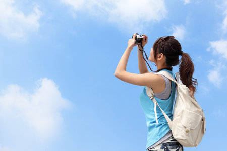 Happy woman traveler photo by camera with blue skyの写真素材