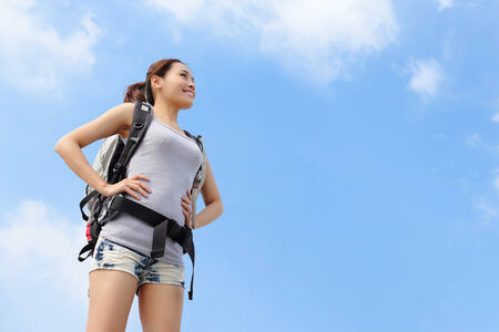 happy woman with backpack raised arm hands and looking to sky on the tpo of mountains. asianの写真素材