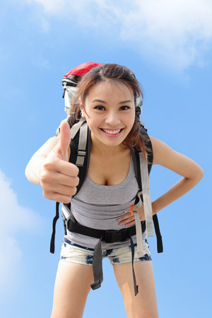 happy woman mountain hiker show thumb up with sky background. asianの写真素材