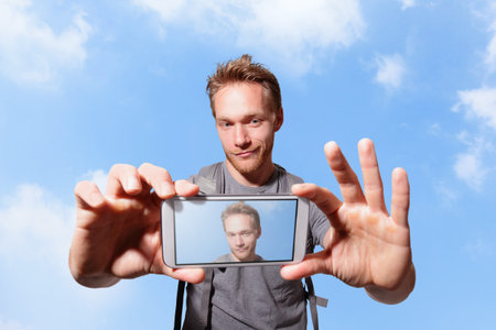 happy man selfie by smart phone with sky background, caucasian
