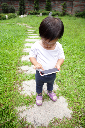 Outdoor portrait of child using a digital tablet or smart phone - asianの写真素材