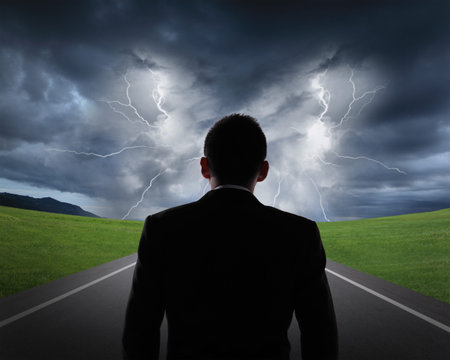 silhouette of business man look rainstorm clouds and lightning with asphalt road and grass, business...