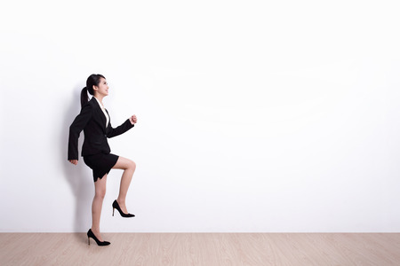 Successful business woman walking with white wall background, great for your design or text, asianの写真素材