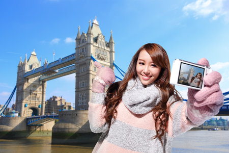 Happy woman tourist travel in london and photo selfie by camera with Tower Bridge in United Kingdom,...