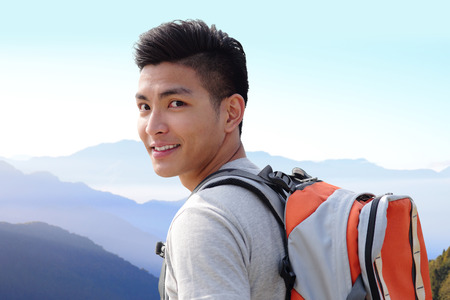 Successful man mountain hiker with backpack on the top of mountains. asianの写真素材