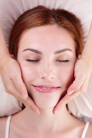 Beautiful young woman enjoy face massage at spa, caucasian beautyの写真素材