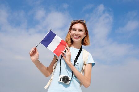 happy young travel woman holding France French flag with sky backgroundの写真素材