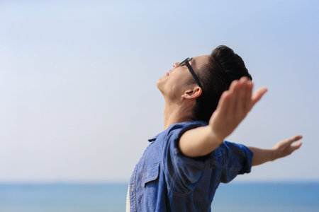 Carefree and free man raised hands and looking to a sky, asian