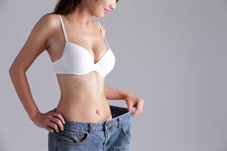 woman shows weight loss by wearing old jeans, asian beauty