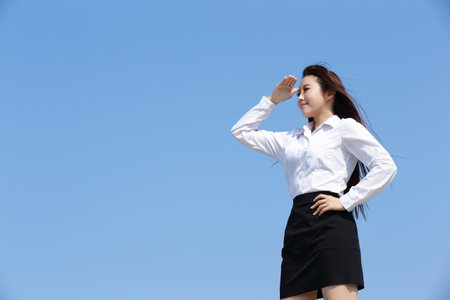 Successful business woman purposefully looking away with blue sky, asian beautyの写真素材