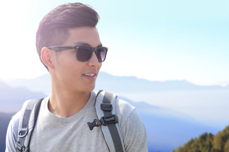 Successful man mountain hiker with backpack on the top of mountains. asianの写真素材