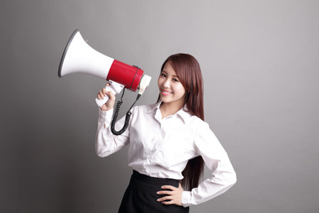 Business woman screaming with a megaphone isolated on gray background, asian beautyの写真素材