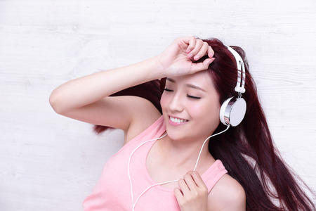 Young woman enjoying the music and relax lying at home, asian beautyの写真素材