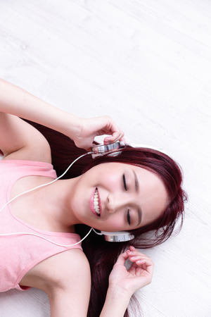 Young woman enjoying the music and relax lying at home, asian beautyの写真素材