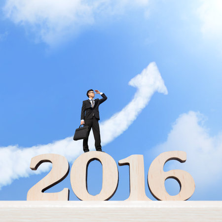Happy new year for 2016 - Successful business man purposefully looking away and celebrating on wood...