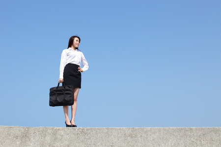 Successful business woman purposefully looking away with blue skyの写真素材