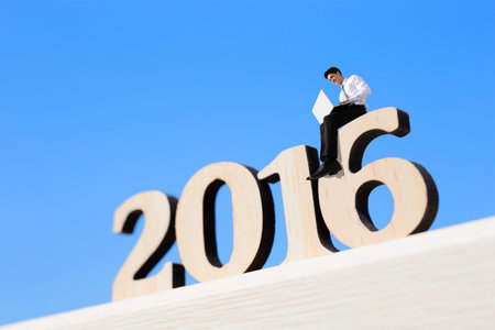 Happy new year for 2016 - success business man with laptop computer and sitting on wood numberの写真素材
