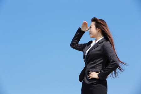 Successful business woman purposefully looking away with blue sky, asian beautyの写真素材