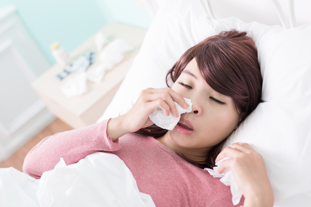 Sick Woman sneezing into Tissue. Flu and Woman Caught Cold.の写真素材