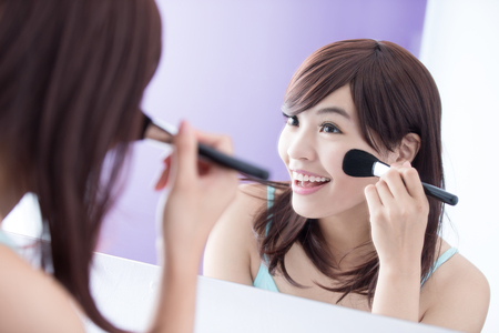 Close up of Smile woman with makeup brushes near face and look mirror. asian beautyの写真素材