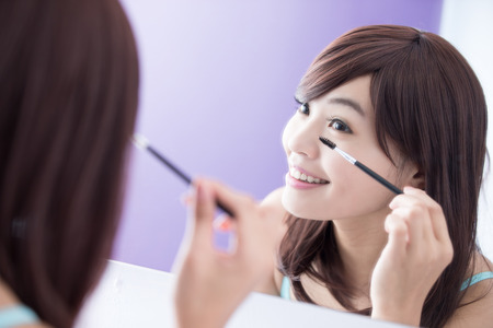 Close up of Smile woman applying mascara on her long eyelashes and look mirror. asian beautyの写真素材