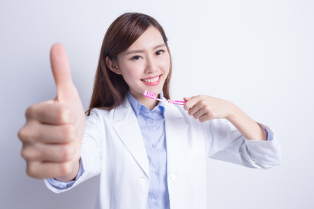 Smile woman dentist doctor teach you brush teeth and show thumb up. asianの写真素材
