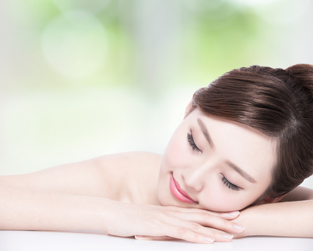 Charming woman face Smile enjoy spa and massage while lying with green background, asian girlの写真素材