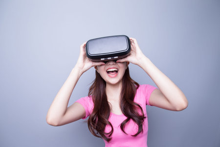 Excited happy woman watching the virtual reality headset, asian beautyの写真素材
