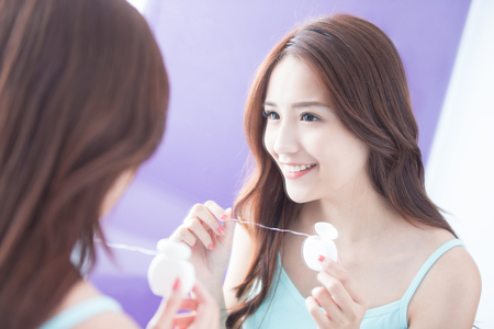 Close up of Smile woman clear teeth by floss and look mirror. great for health dental care concept. asian beautyの写真素材