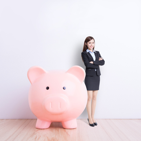business woman stand with pink piggy bank with white wall background, great for your design or text, asianの写真素材