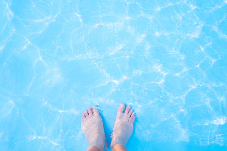 Barefoot and blue swimming pool rippled water background, great for your background and textureの写真素材