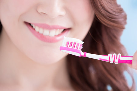 Beautiful young woman with health teeth and charming smile.holding the tooth brush, Isolated over...