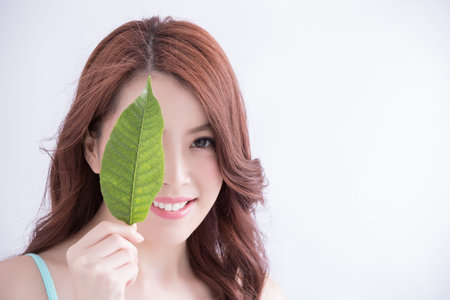 beautiful woman face portrait with green leaf , concept for skin care or organic cosmetics , asian beautyの写真素材
