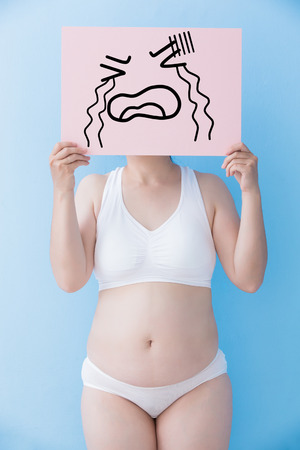Fat overweight woman take crying billboard and body with blue background, asianの写真素材