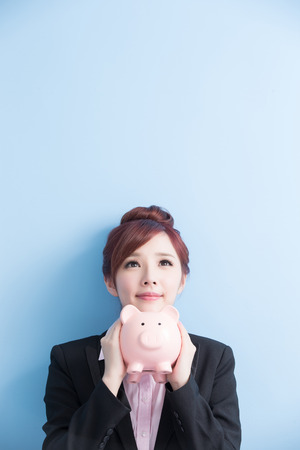 business woman take pink piggy bank look some where with isolated on blue backgroundの写真素材