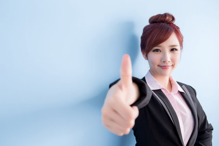 business woman is smile to you and thumbs up isolated on blue background, asianの写真素材