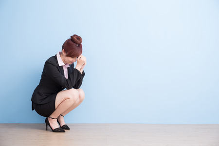 business woman is painful and unhappt on the floor with blue background, asianの写真素材