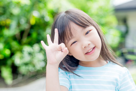 little girl smile happily and show ok to you in the park,asianの写真素材