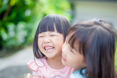 two little girls smile happily in the park,asianの写真素材