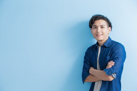 man student smile to you isolated on blue background,asianの写真素材