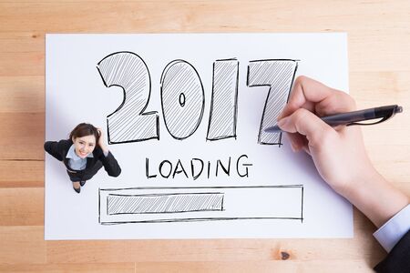 Business people writing 2017 new year loading text on the paper and woman smile to youの写真素材