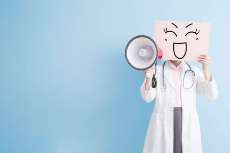 woman doctor take smile billboard and microphone isolated on blue background,asianの写真素材
