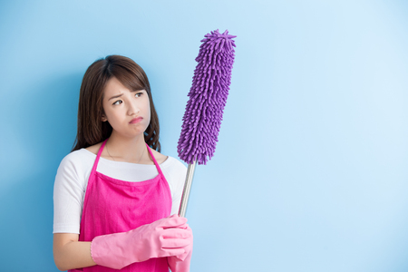 beauty housewife take feather duster and unhappy isolated on blue background, asianの写真素材